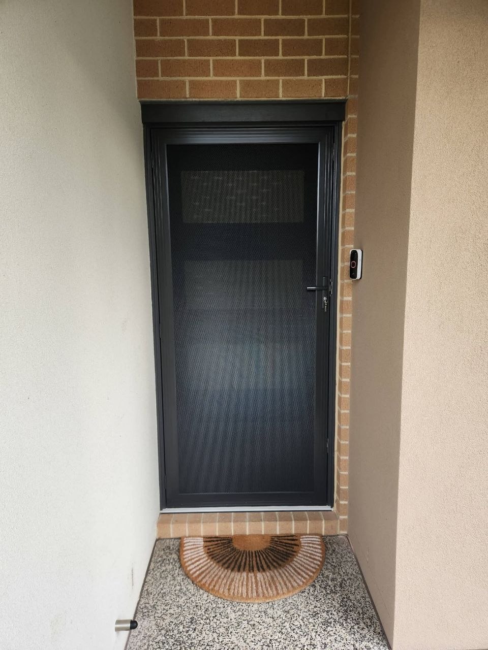 Black security screen door fitted at brick entrance with intercom