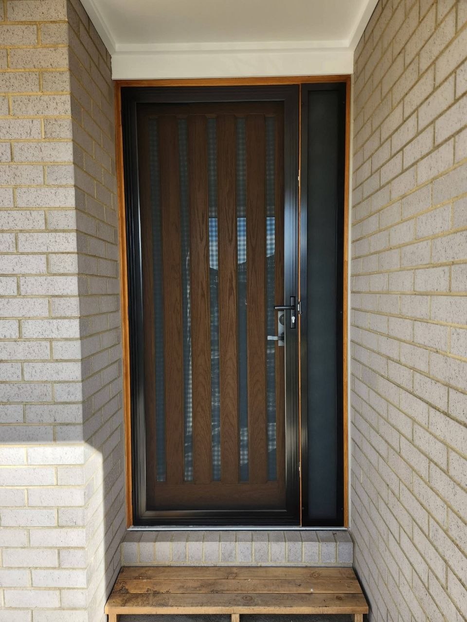 Black security door with glass insets, brick wall surround